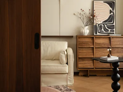 A well-lit living room with a couch near a doorway, featuring vases and a book on a table