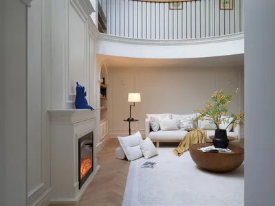 Cozy modern living space with a white couch, two chairs, and wood paneling walls, featuring a fireplace