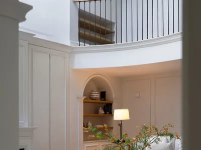 A warm and inviting living area with a wooden table, white couches, and a potted plant, surrounded by books and comfortable seating