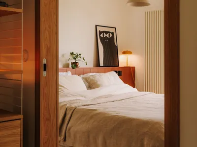 Cozy bedroom with a large bed, two potted plants, and a vase, set against a neutral background