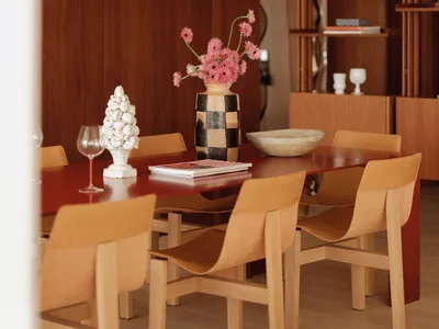 Dining area with a wooden table, three chairs, and a vase, set in a luxurious interior