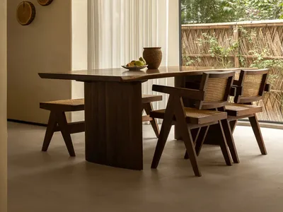 Warm and inviting dining space with a wooden table and chairs, surrounded by natural light and fruit