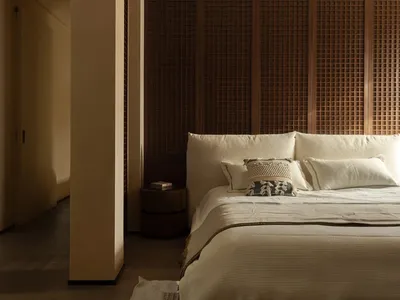 A well-lit bedroom with a large white bed, wooden headboard, and two pillows, set in a calm and inviting atmosphere