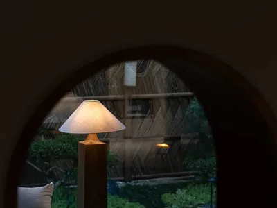 Cozy living space with a couch, two chairs, and a lamp, illuminated by natural light from a window