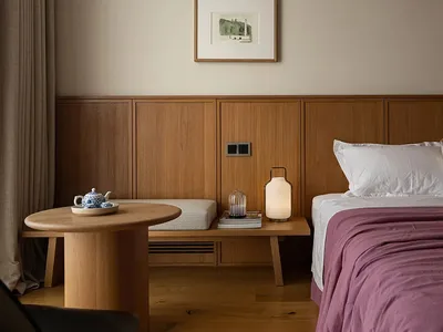 Cozy bedroom with a large bed, wooden nightstands, and a table with a bowl, illuminated by a lamp