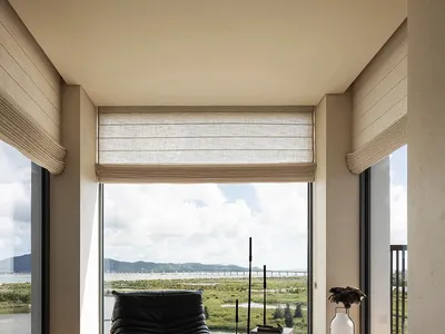 Cozy living space with a black leather chair, books, and a vase, set against a neutral background