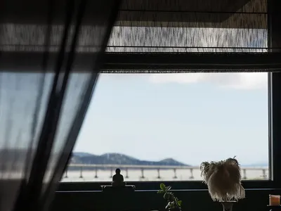 Cozy dining space with a table, chairs, couch, and ocean view, decorated with vases, plants, and a bowl, providing a relaxing atmosphere