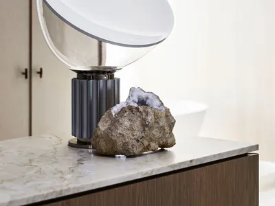 A clean bathroom with a sink, toilet, and large white light fixture, accompanied by two rocks on the countertop