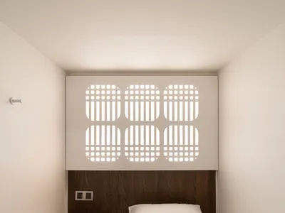 一間現代化的書房，白色被套和棕色床頭板，書桌，椅子，透過窗戶自然光照明