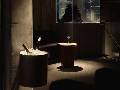Cozy living room with a large aquarium, a couch, and a dining table, featuring wood and glass materials in a dimly lit space