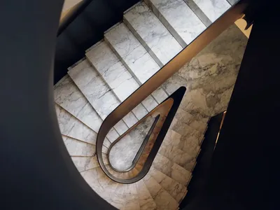 A black and white photograph of a curved marble staircase with a sophisticated and timeless appearance