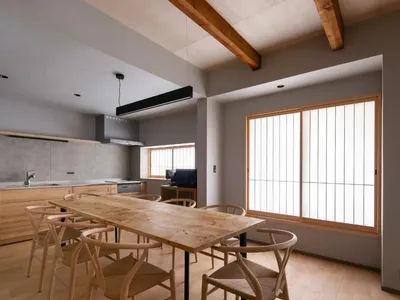 一間現代廚房和餐廳區域的木桌和椅子,冰箱,爐子,和大餐桌,被自然光線和陽光包圍著