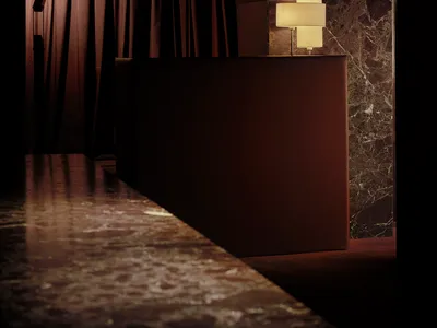 Dimly lit hotel lobby with a marble countertop, a brown table, and a lamp, set against a neutral background