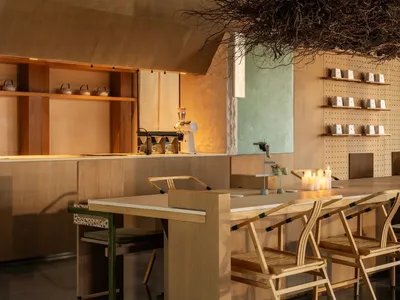 A modern kitchen with wooden floors, a wooden dining table, and a cozy atmosphere created by soft warm lighting
