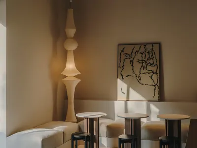 a living room with a couch, chair, and dining table in a neutral color palette, with soft warm lighting and natural light from windows
