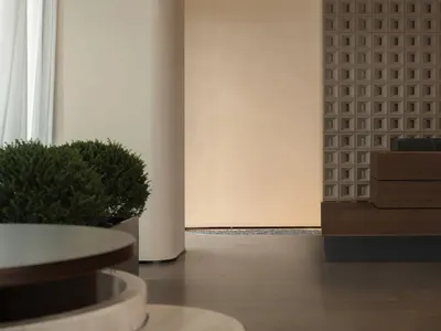 Cozy living space with a wooden floor, a white wall, a bench, and a potted plant