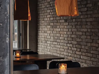 Dining area with tables, chairs, candles, and brick walls, creating a warm and inviting atmosphere