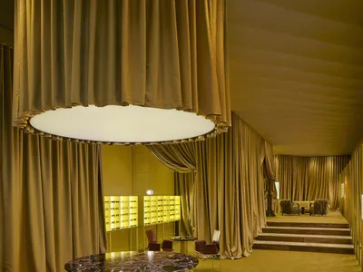 A modern dining room with a yellow color scheme, a dining table, chairs, a couch, a chair, and a large window with natural light