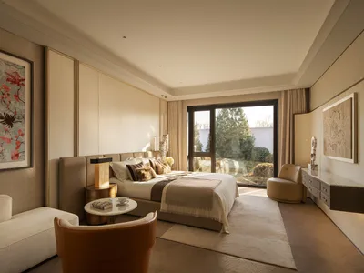 Cozy bedroom with a bed, chair, and couch, surrounded by a beige color scheme, with natural light and wood and fabric materials