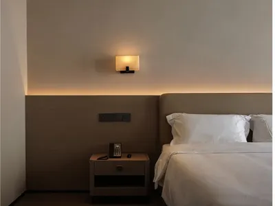 A well-lit bedroom with a wooden bed frame, nightstand, and lamp, creating a warm and inviting atmosphere