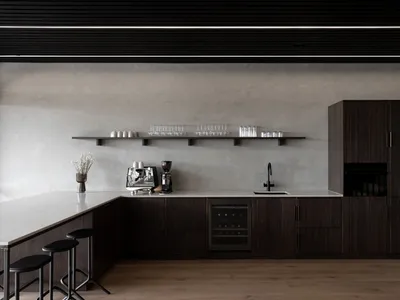 Modern kitchen with wooden cabinets, a black refrigerator, and dim lighting, featuring a sink, microwave, coffee maker, and decorative items