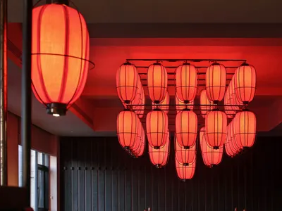 一間現代餐廳紅色和黑色配色設計，擁有餐廳區域、吧台和柔光照明