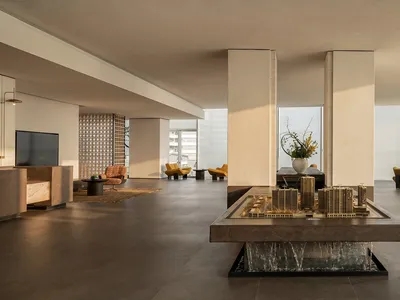 A modern living room with a large window, natural light, chairs, a couch, dining table, and vase, creating a comfortable and inviting atmosphere