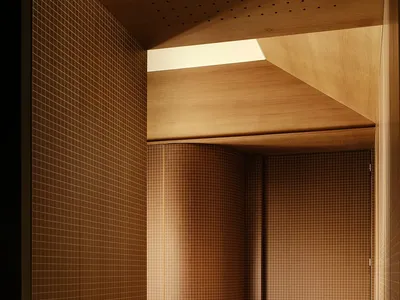 A dimly lit bathroom with a wooden door, open to reveal the interior of the room