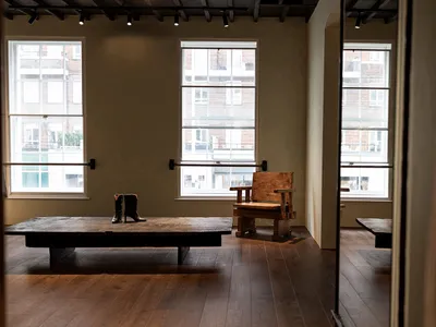 Warm and inviting living room with a wooden floor, a wooden table, a bench, and a large window allowing natural light to enter