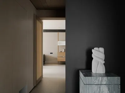 A black and white living room with a stone pedestal, a white sculpture of a hand, a couch, and a dining table, in a modern and minimalist style