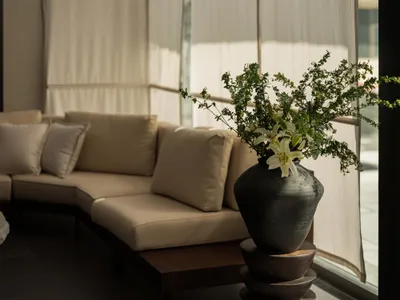 A well-lit living room with a couch and a vase with flowers on a table, creating a comfortable and inviting atmosphere