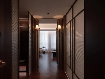 Dimly lit hotel hallway with a wooden floor, a glass door, a couch, a chair, and a vase on a surface