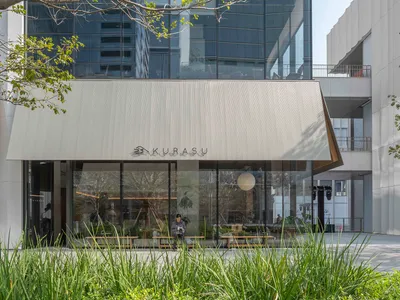 一個餐廳建築物,外面有大窗戶,招牌,樹,在中性顏色方案中,自然光線穿透進入