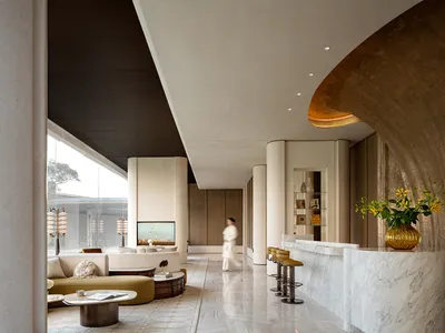 Well-lit hotel lobby with a modern design, featuring a large counter, couch, and dining table, with a woman walking through, and natural light streaming in through the windows