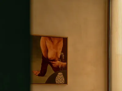 A calm and inviting bathroom with a woman's picture on the wall, a tiled floor, and a white wall, with a vase on display
