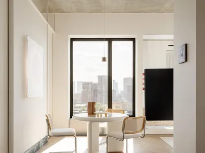 Cozy modern living room with a dining table, chairs, couch, and large window offering a city view