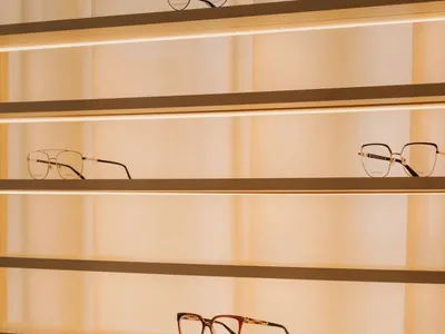 A display case with glass shelves showcasing a variety of eyeglasses in different styles and colors, illuminated for a visually appealing presentation