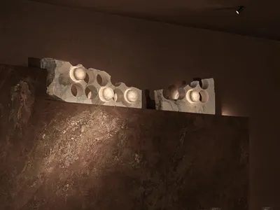 Elegant dining room with a marble wall, a stone wall, a dining table, chairs, wine glasses, a vase, and a bowl