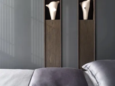 A cozy bedroom with a wooden shelf and two vases, a bed visible in the background