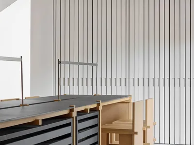 一間現代廚房飯廳空間，木地板和白牆，具有餐桌、椅子和擺放廚具的柜台，以及靠近窗戶的自然光線照射