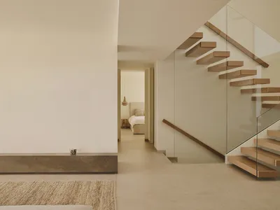 Cozy bedroom with a white wall, brown floor, and a bed in the corner, featuring a rug and a cup on the floor