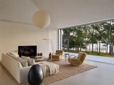 Cozy modern living room with a white couch, a chair, and a fireplace, surrounded by natural light from a large window