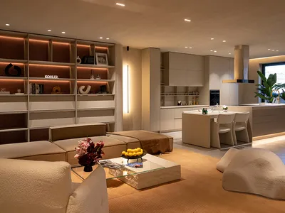Cozy living room with a large couch, dining table, and kitchen area, featuring modern furniture and decorative vases and bottles, set in a dimly lit space