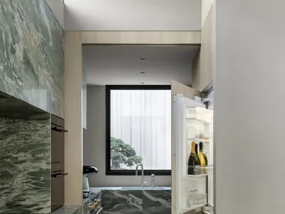Well-lit kitchen with a white refrigerator, sink, and marble countertop, set against a bright and airy background