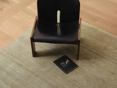 一間舒適的生活空間，裡面有一個黑色椅子，毯子上散落著一本書，給人以放鬆的感覺