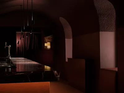 Dark modern bar with a marble counter, brown color scheme, and dim lighting