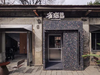 Outdoor restaurant with a stone exterior, a stone wall, and a stone door, set in a natural environment with earthy tones and natural lighting