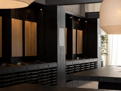 A dimly lit modern kitchen with a wooden floor, black counter, and wooden cabinets and drawers