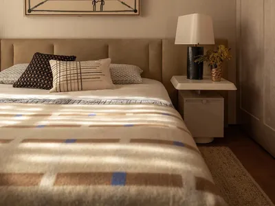 一間舒適的床室，配備了床、燈泡和畫作，呈現時尚風格的木材和紡織品材料，自然光線照射
