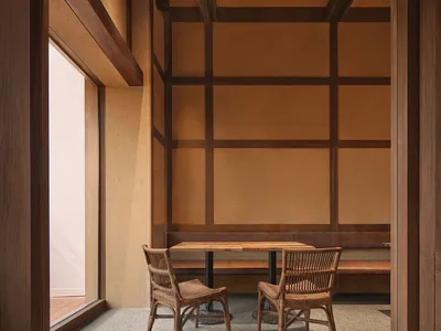 A warm and inviting dining area with a wooden floor, a dining table, chairs, and a bench, lit by natural sunlight